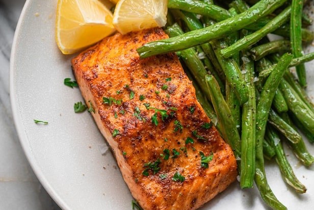 Salmón frito con judías verdes y limón en un plato