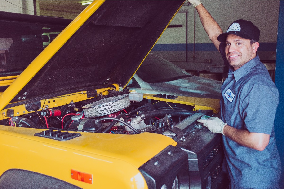 Technician checking under the hood of a car.