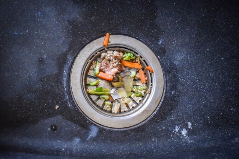 Food sitting in the drain of a sink.