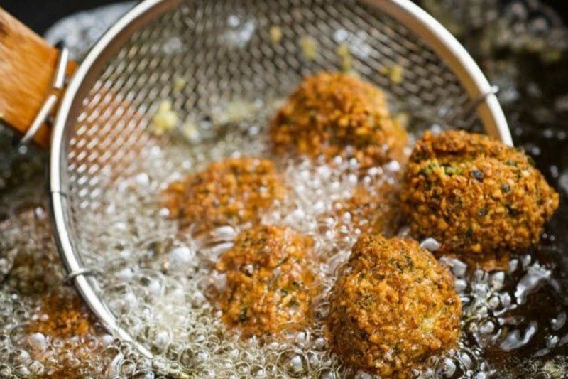 Falafel assaisonné Hawajj dans de l'huile et une passoire.