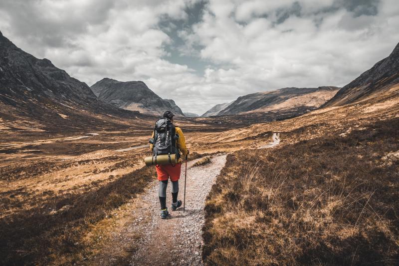 A man treks through the Scottish highlands with mountains all around