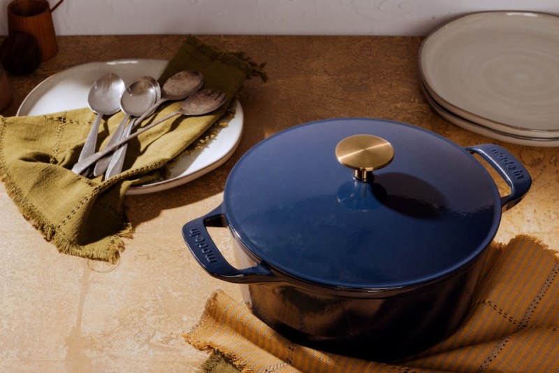Blue dutch oven sitting on a counter with dishes and flatware