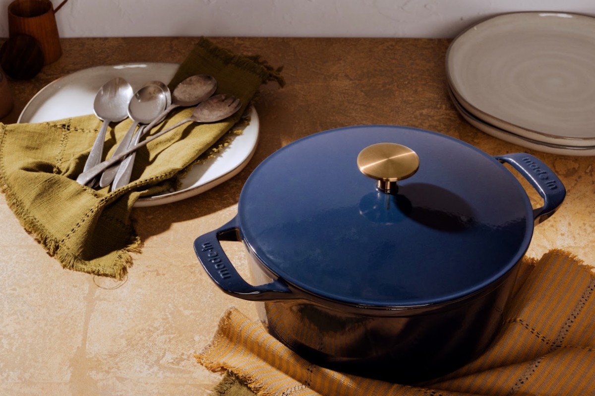 blue dutch oven sitting on a counter with dishes and flatware.