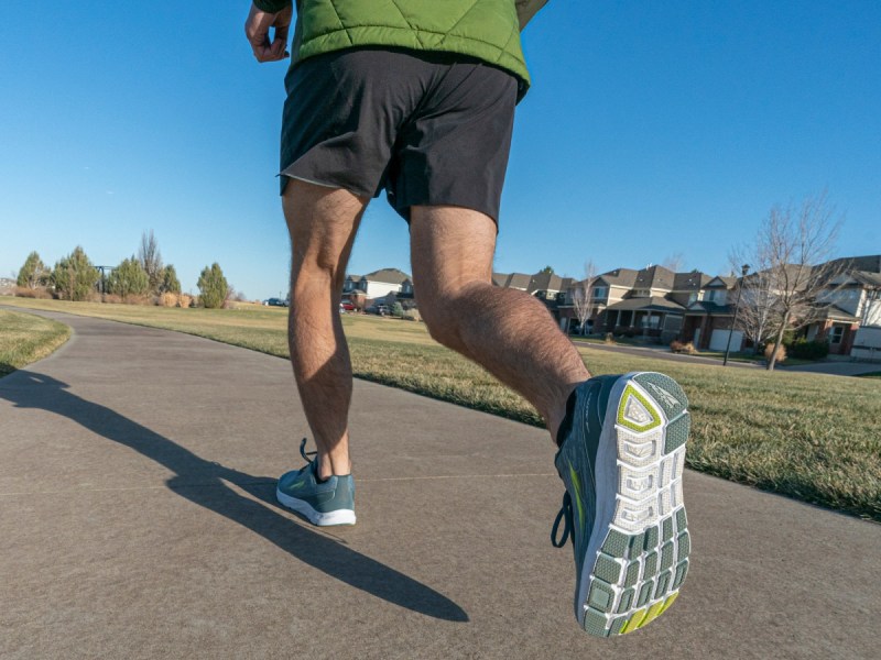 Man wearing Alta running shoes on condo complex walkway.