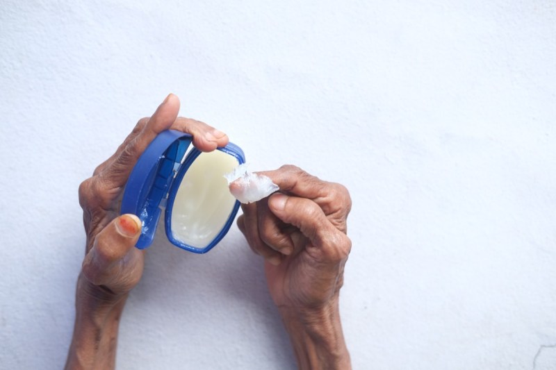 pair of hands getting petroleum jelly out of a jar.