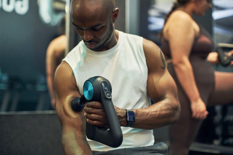 A man massages his arm with a Theragun Pro.