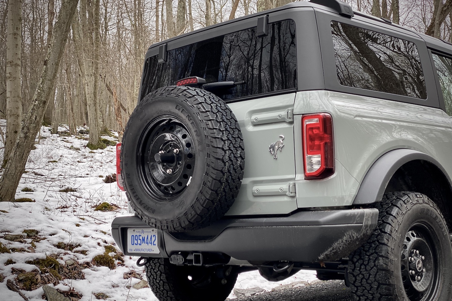 Close up of spare tires on 2021 Ford Bronco on a gravel trail with snow in the back.