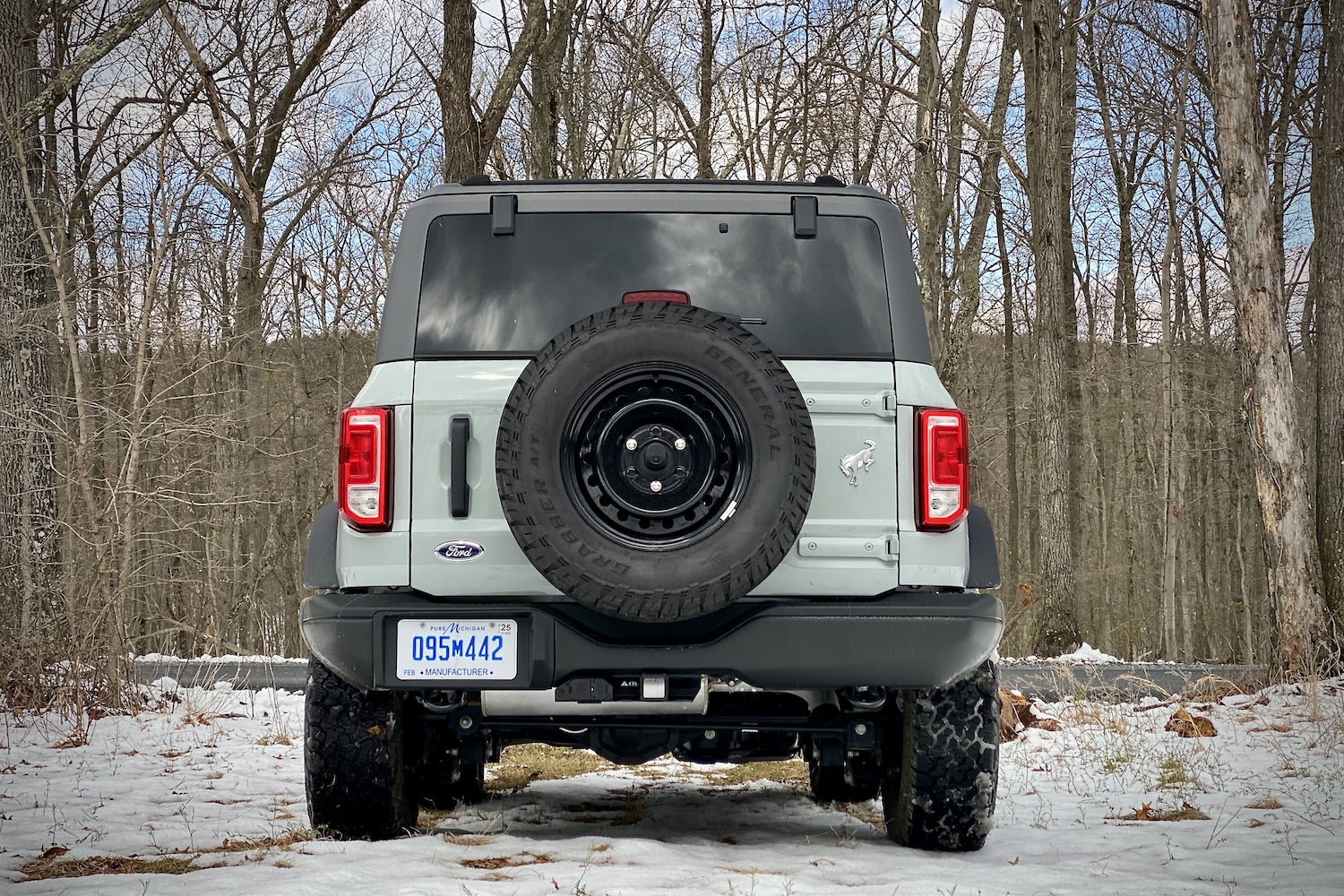 Close up of 2021 Ford Bronco rear end on a snowy field with trees in the back.