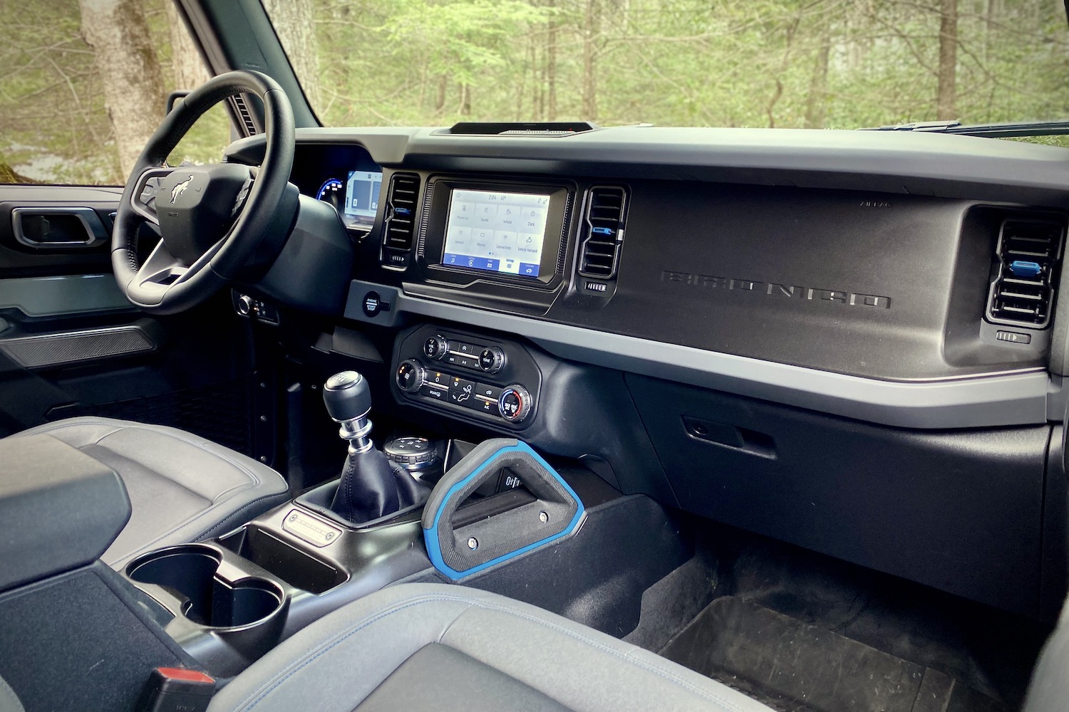 Dashboard and center console in 2021 Ford Bronco from passenger side with trees in the back.