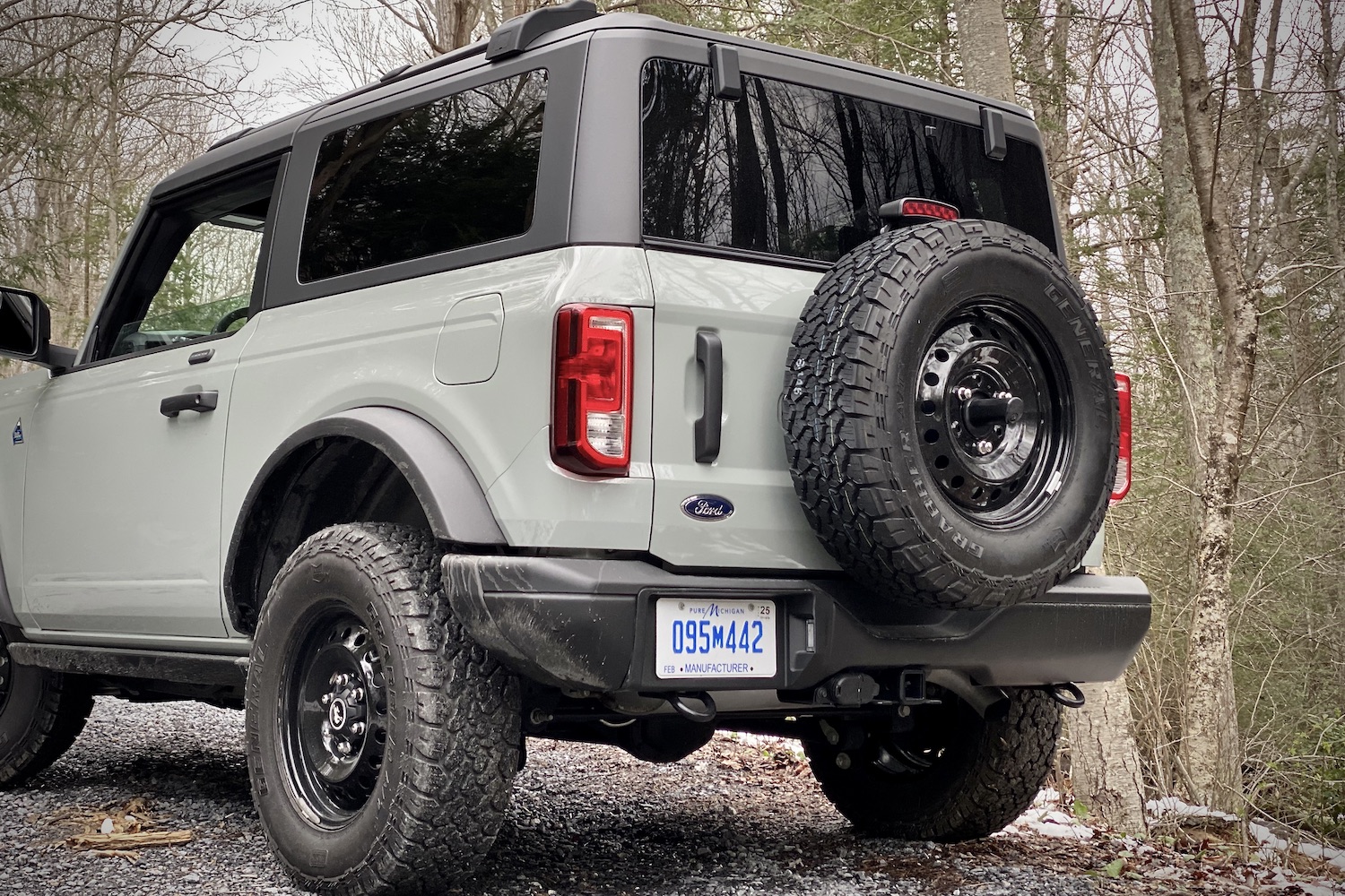 2021 Ford Bronco close up of rear end from driver's side on a dirt trail in front of trees.