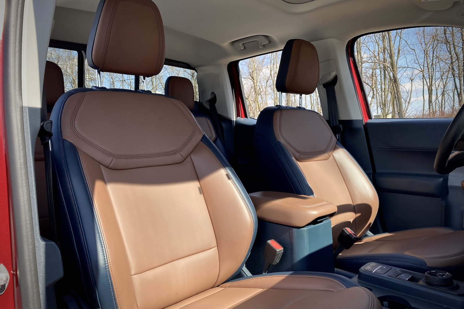 Front seats in the 2022 Ford Maverick from the passenger side with trees in the back.
