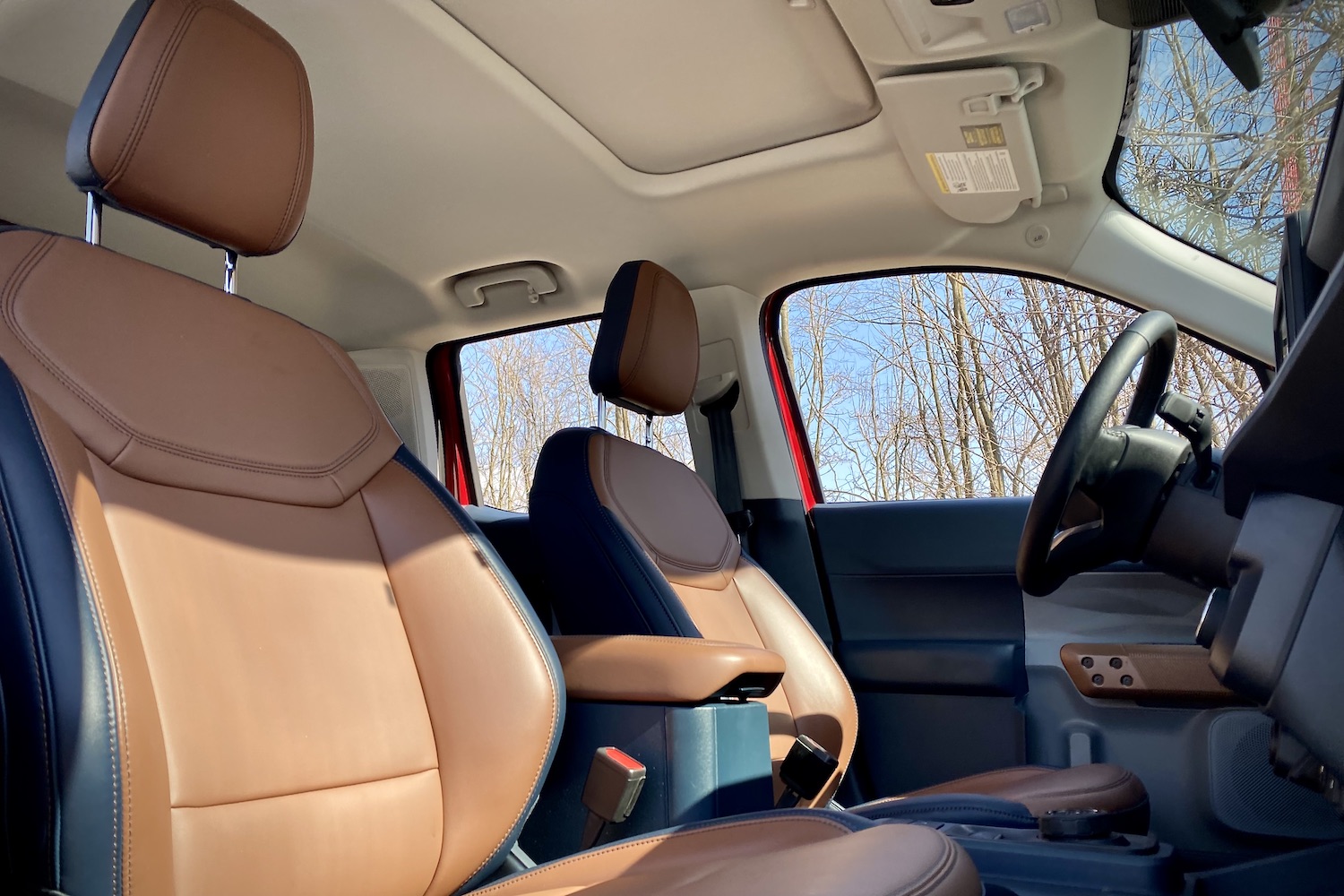 Front seats in the 2022 Ford Maverick from passenger side with blue skies and trees in the back.