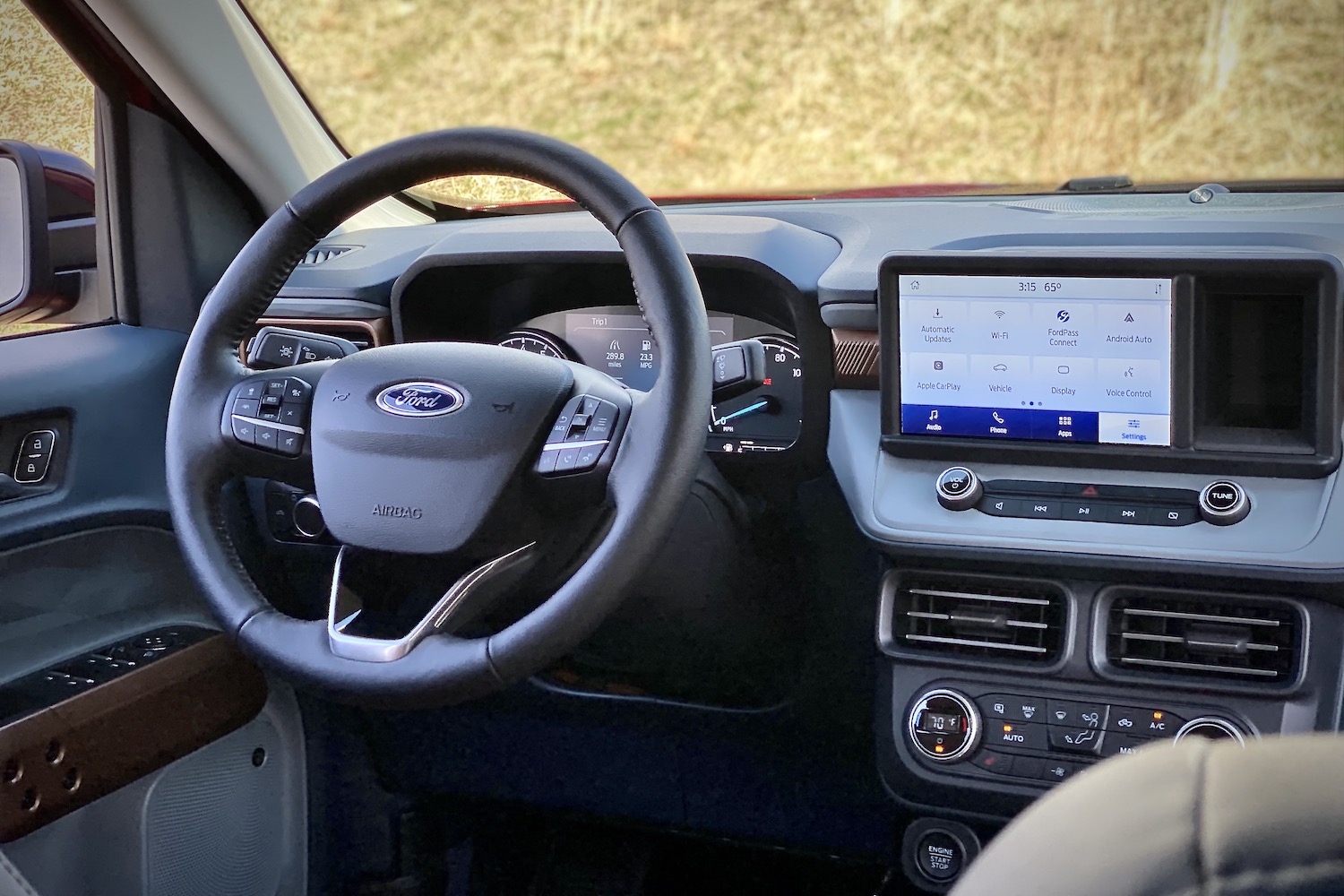 Close up of 2022 Ford Maverick steering wheel and central touchscreen with grass in the back.