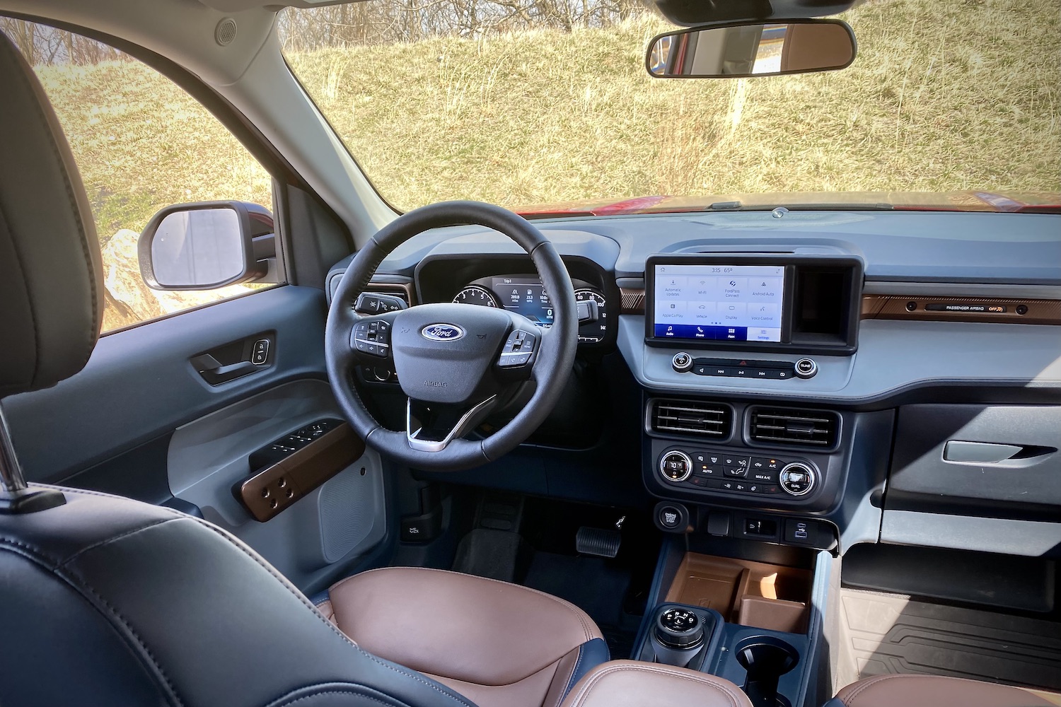 2022 Ford Maverick steering wheel and center console with grass in the back.