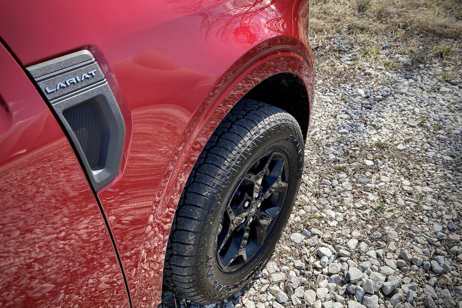 Close up of 2022 Ford Maverick front right wheel from passenger angle on a gravel parking lot.