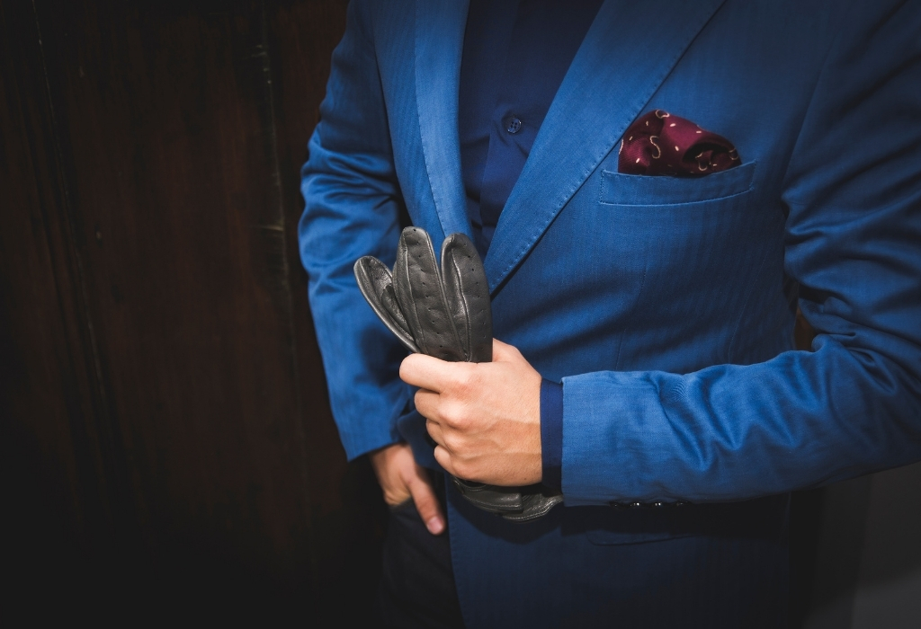 Man in a blue suit jacket holding a leather glove