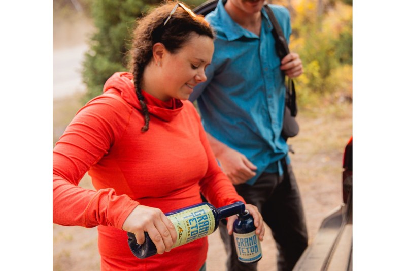 A woman hiker pours a glass of Grand Teton Potato Vodka.