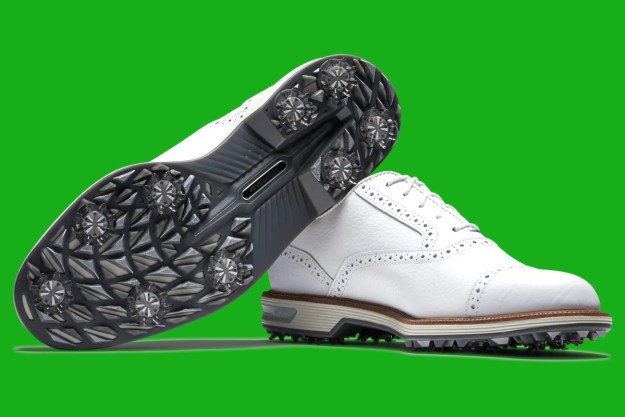 A pair of white golf shoes against a green background