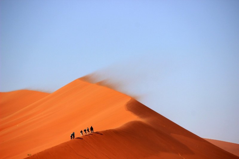 Small group of people hiking the red dunes in Dubai.