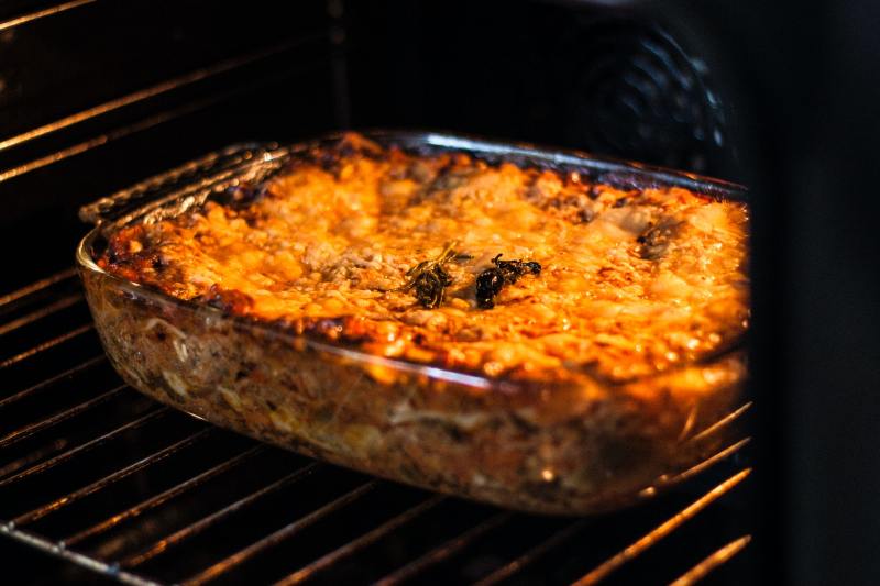 Cheesy lasagna in a glass baking dish in the oven