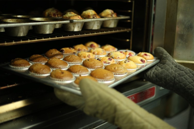Removing muffins in a metal baking dish from the oven