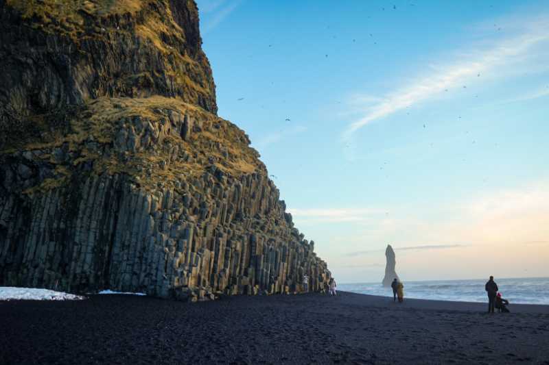 A few people enjoying the black sands of a beach near Vik, Iceland.