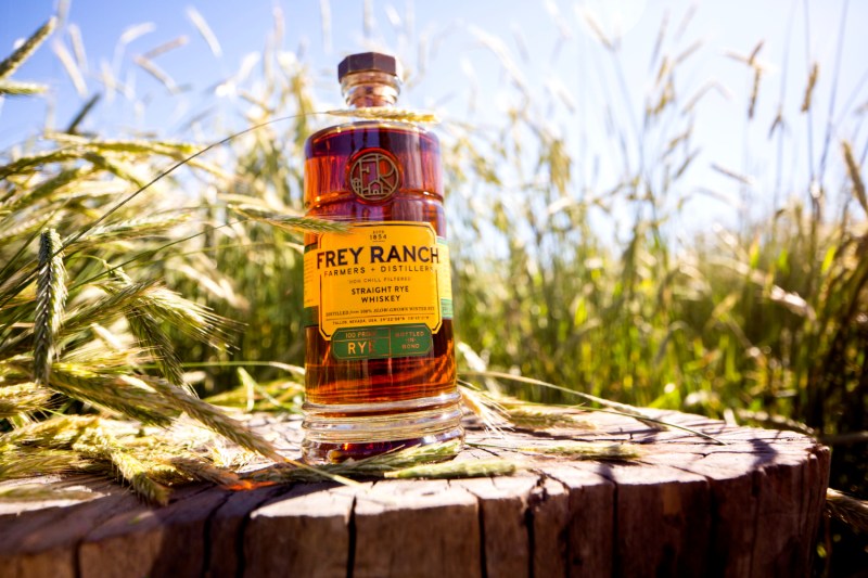 A bottle of Frey Ranch Rye Whiskey in front of some grains