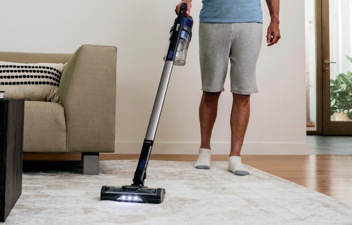 Woman using Shark Dyson cordless vacuum in kitchen