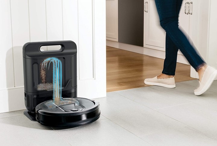 Person walking by self-emptying Shark IQ robot vacuum at docking station