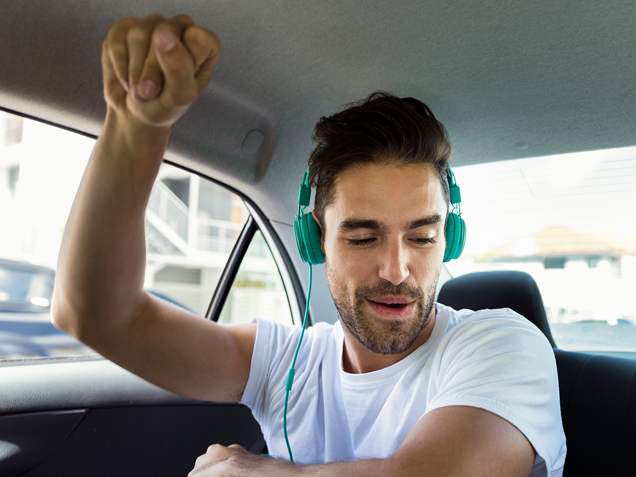 Man listening to Tidal in taxi and dancing.
