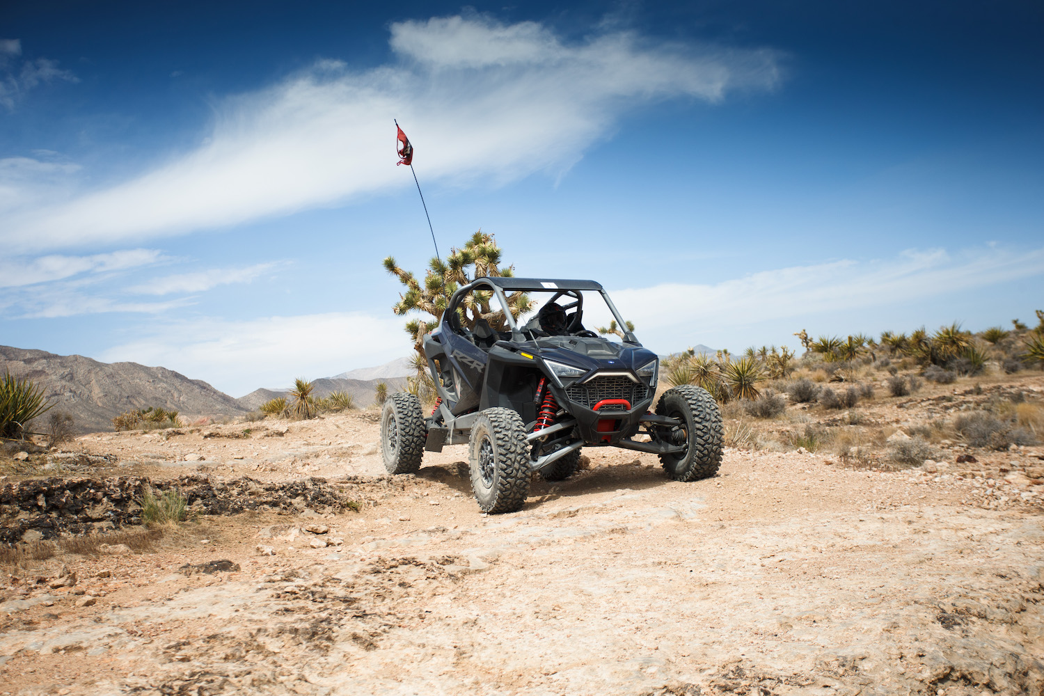 Close up of Polaris RZR Pro R front end driving through a dirt path in the desert.