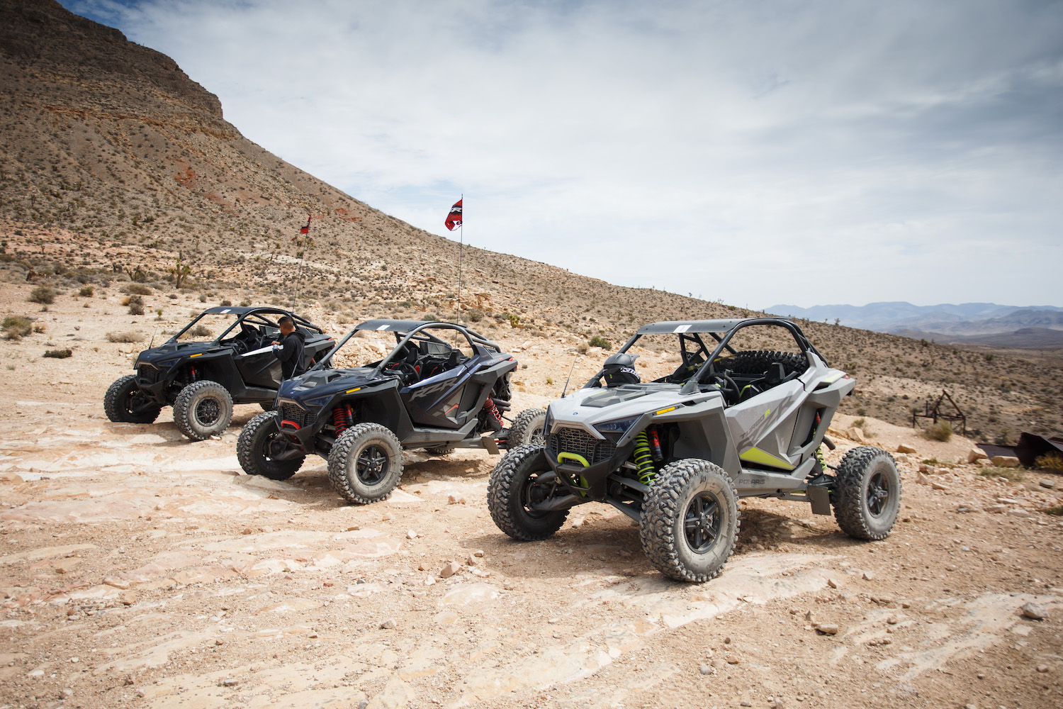 Polaris RZR Pro R and Turbo R from driver's side angle on a dirt path with mountains in the background in the Mojave desert.