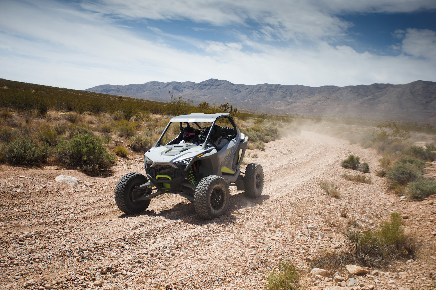 Polaris RZR Turbo R front end angle from driver's side on a dirt trail in the desert with bushes in the background.