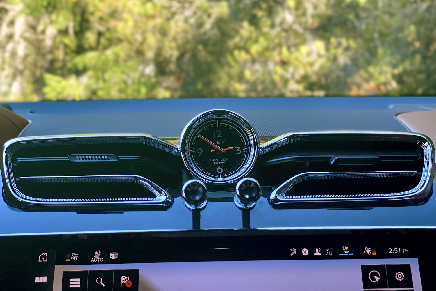 Close up of 2023 Bentley Bentayga EWB analog clock with trees in the back.