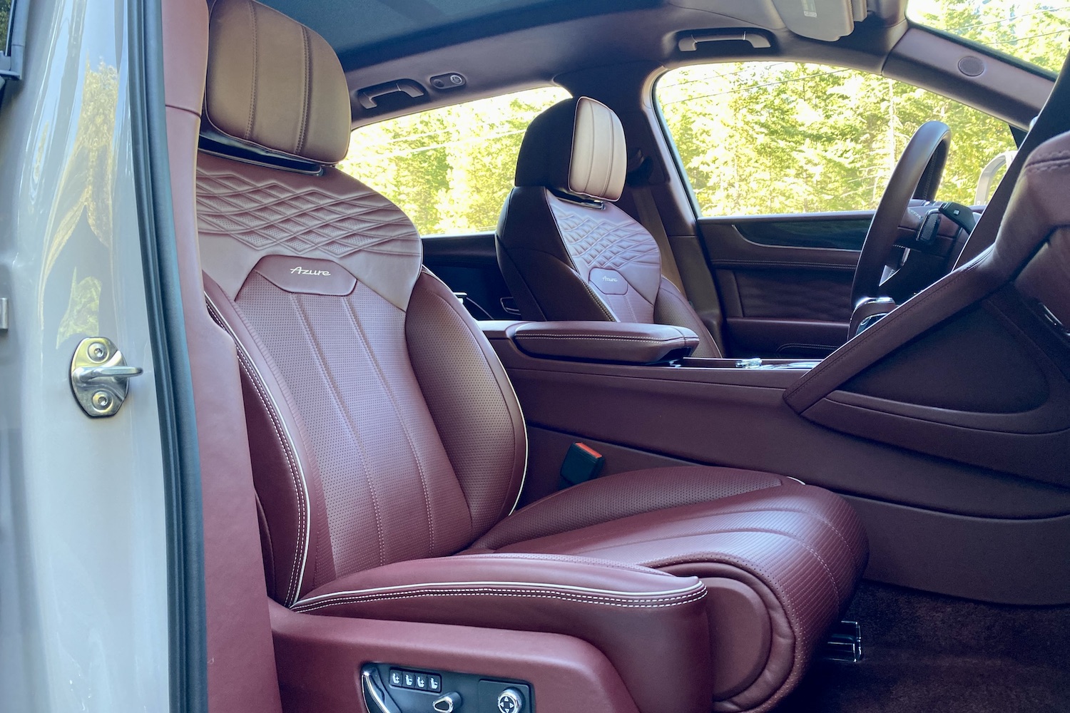 Front seats in 2023 Bentley Bentayga EWB from passenger's side from outside the vehicle with trees in the back.