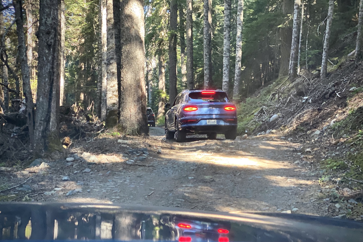 2023 Bentley Bentayga EWB off-roading through the woods near Whistler Olympic Park on a gravel trail with trees surrounding the 