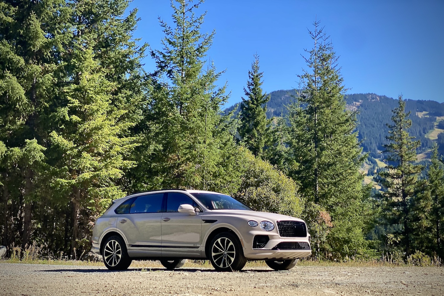 Front end angle of 2023 Bentley Bentayga EWB with trees and mountains in the back.