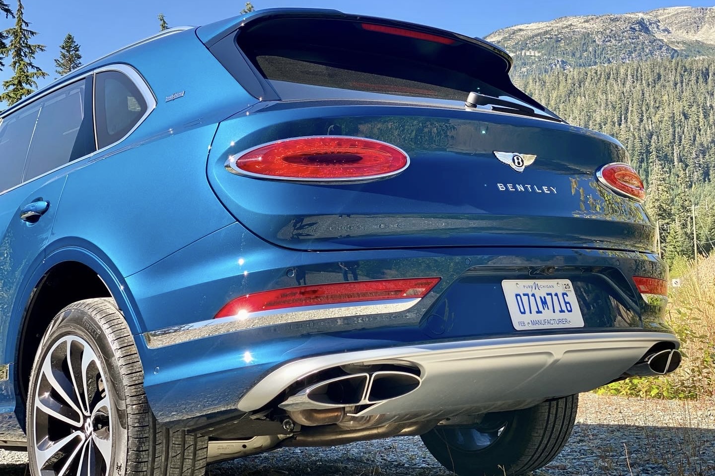 2023 Bentley Bentayga EWB close up of rear end from driver's side on a gravel road with mountains in the back.