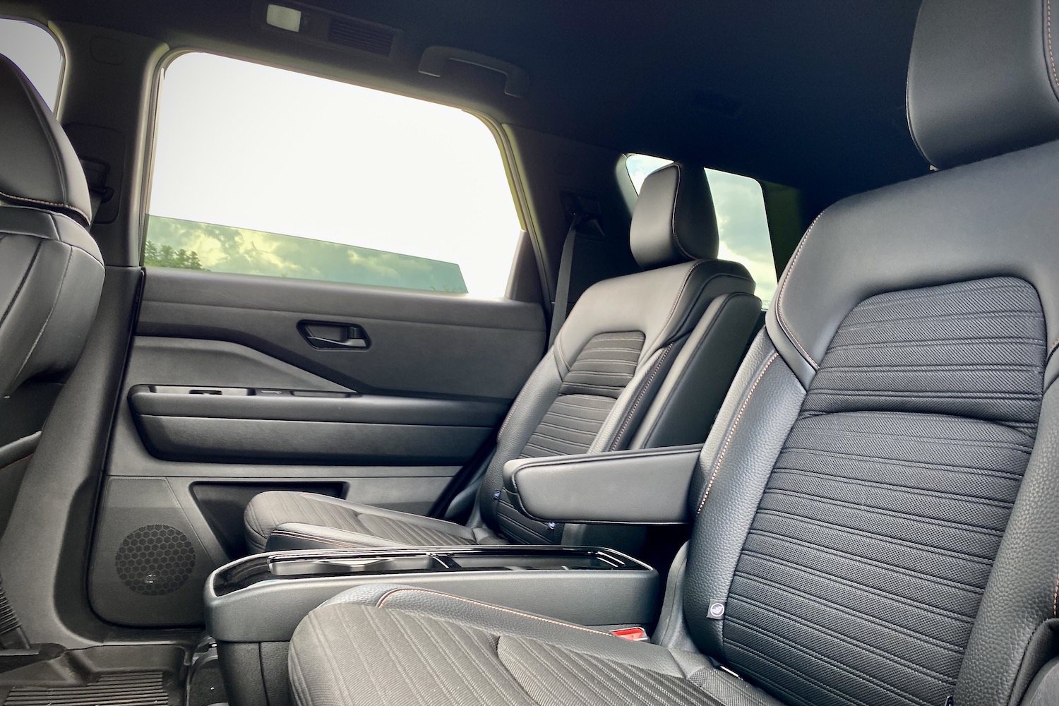 Second-row seats in the 2023 Nissan Pathfinder Rock Creek from the driver's side with blue skies.