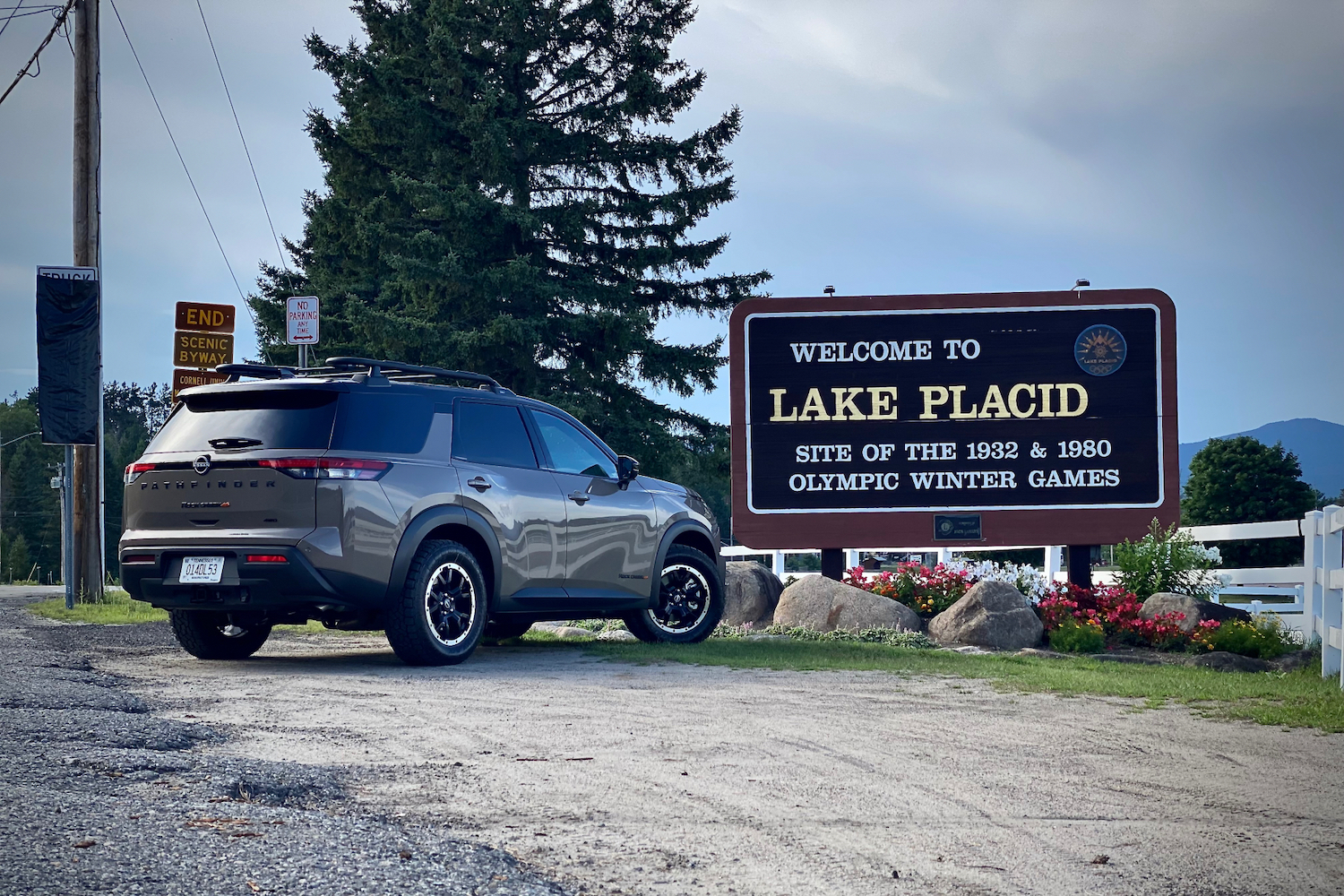 2023 Nissan Pathfinder Rock Creek rear end angle from passenger's side in front of Lake Placid sign.