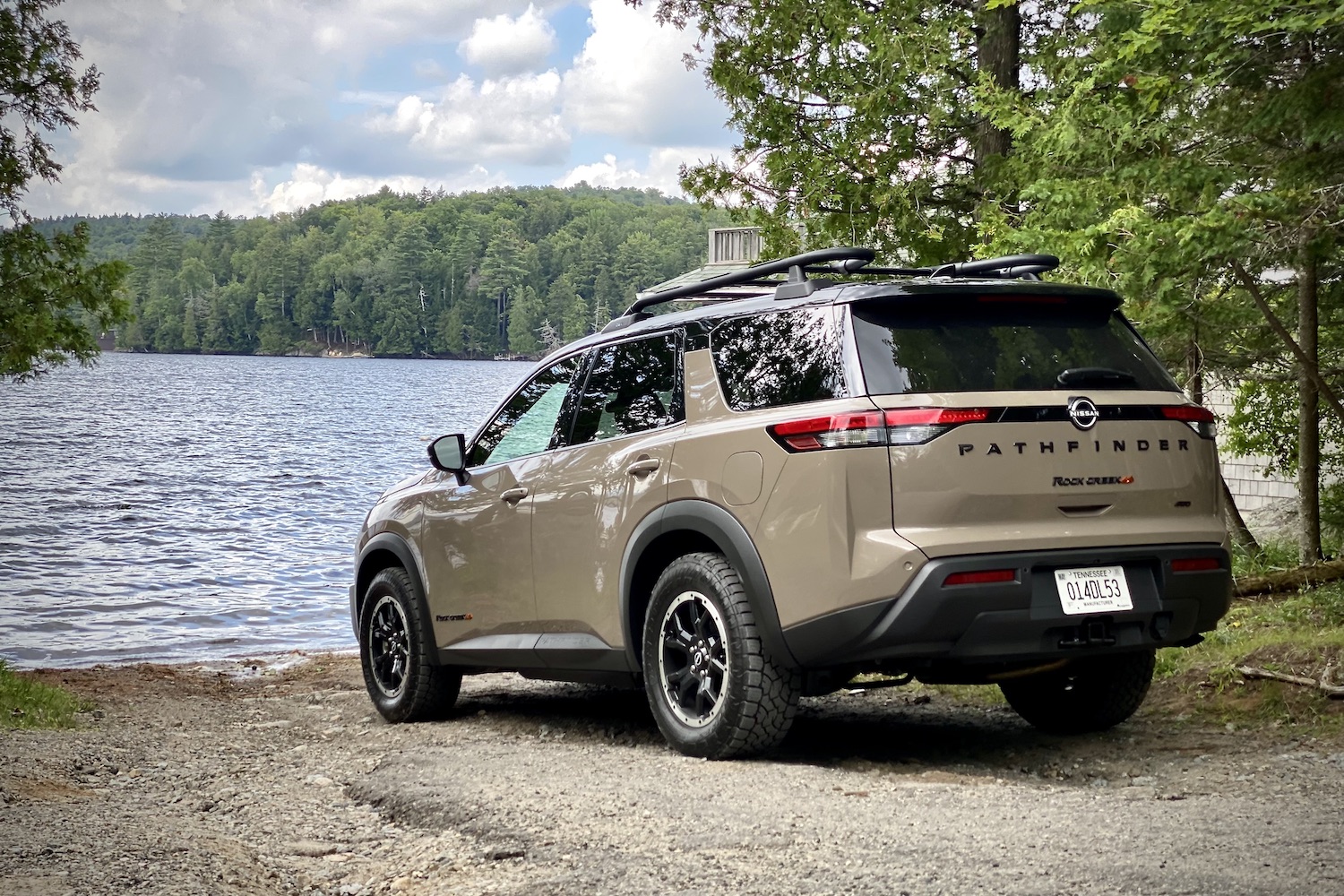 Rear end of 2023 Nissan Pathfinder Rock Creek on a dirt path in front of a lake.
