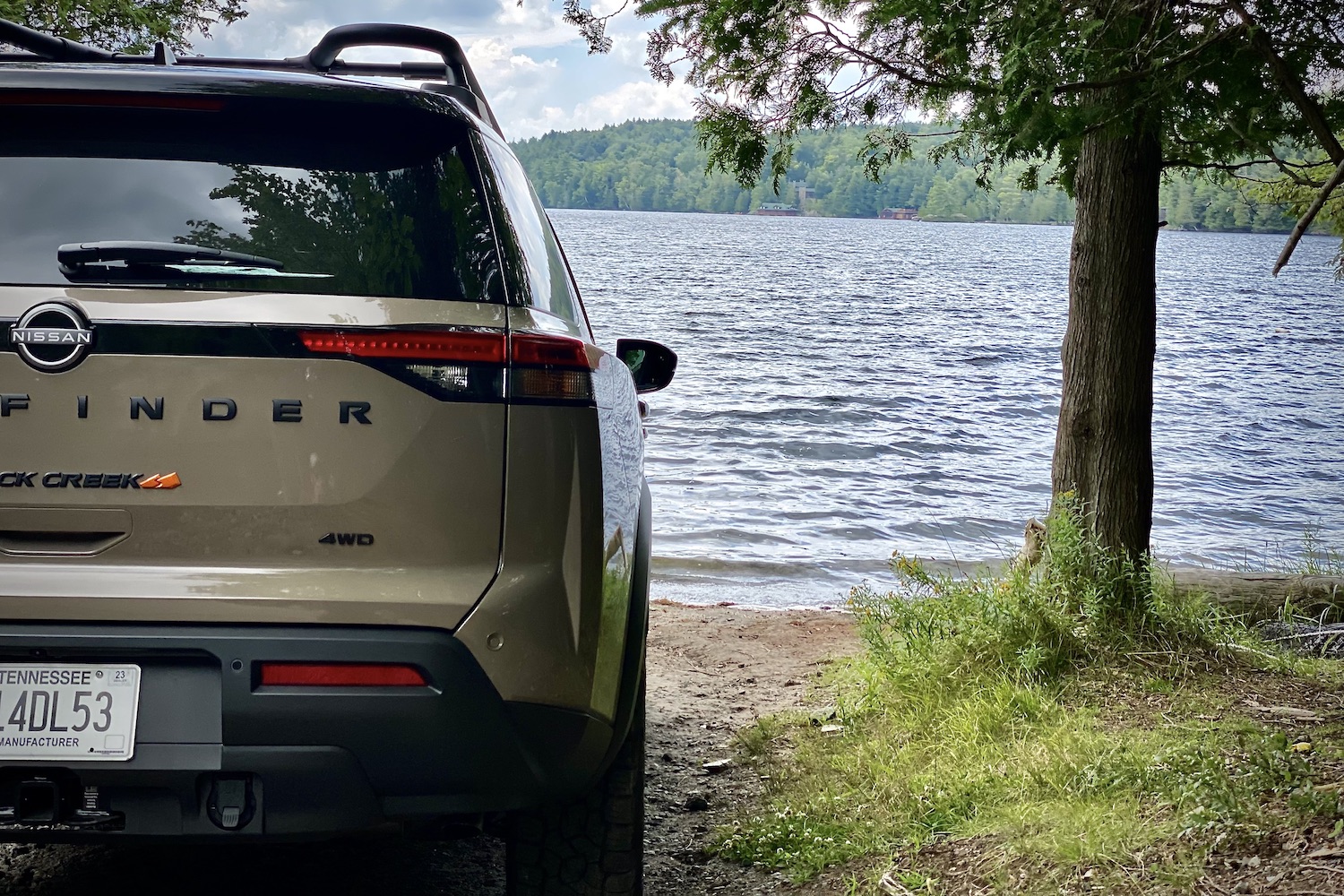 Close up of 2023 Nissan Pathfinder Rock Creek rear end taillight in front of a lake on a dirt trail.