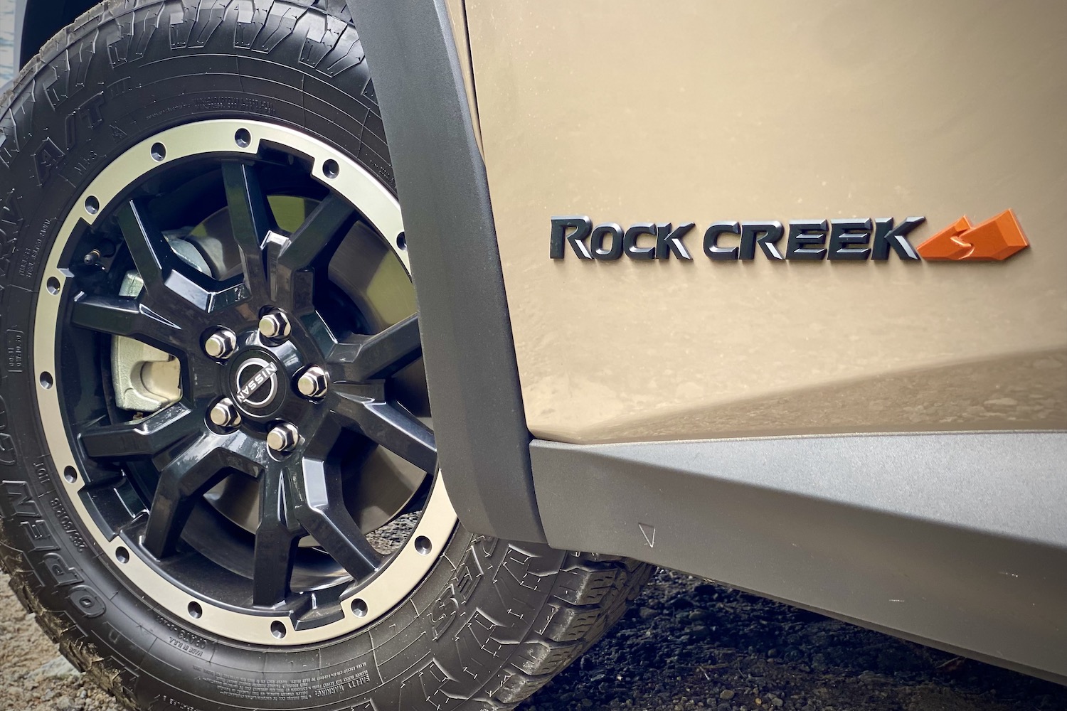 Close up of 2023 Nissan Pathfinder Rock Creek front tire and Rock Creek badge on a dirt trail.