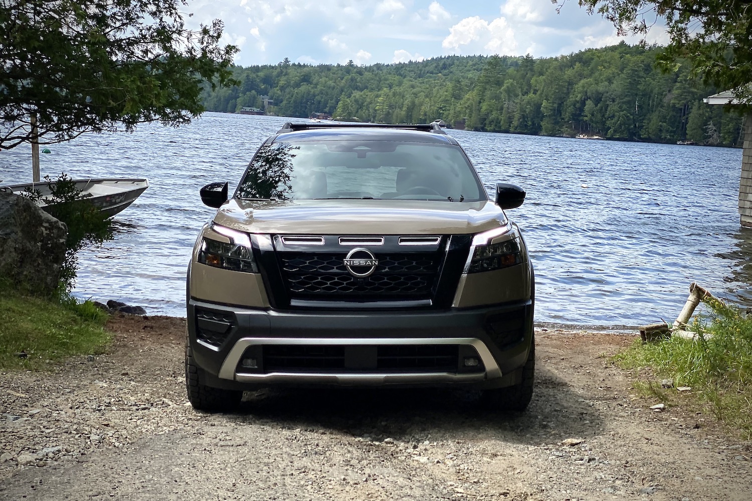 Close up of front end of 2023 Nissan Pathfinder Rock Creek in front of a lake on a dirt path.