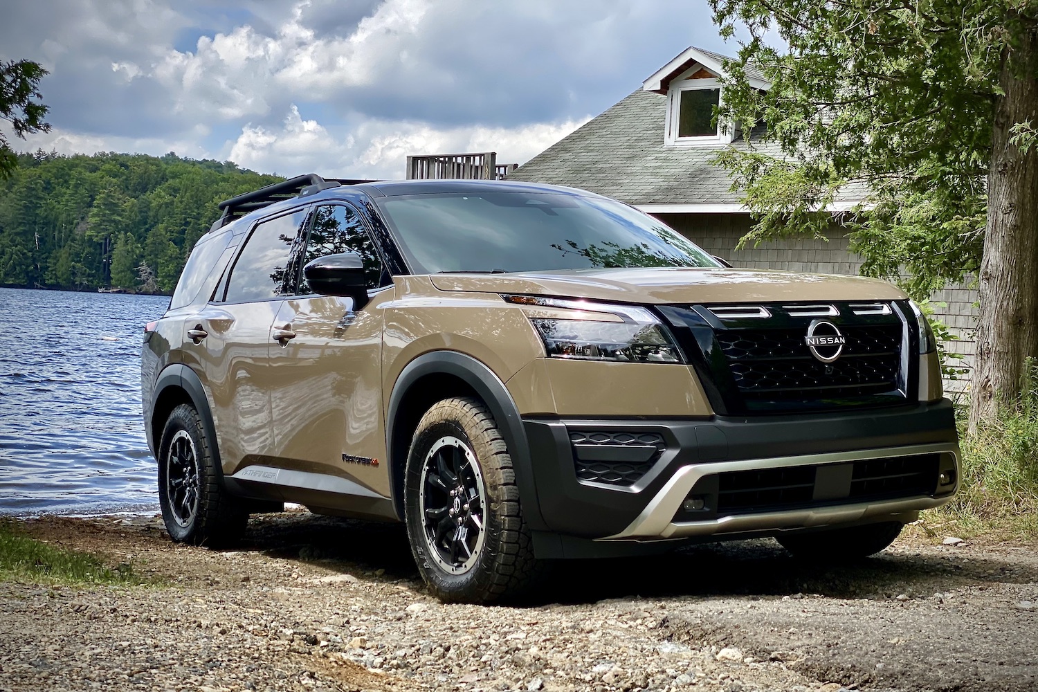 Front end angle of 2023 Nissan Pathfinder Rock Creek on a dirt trail in front of a lake.