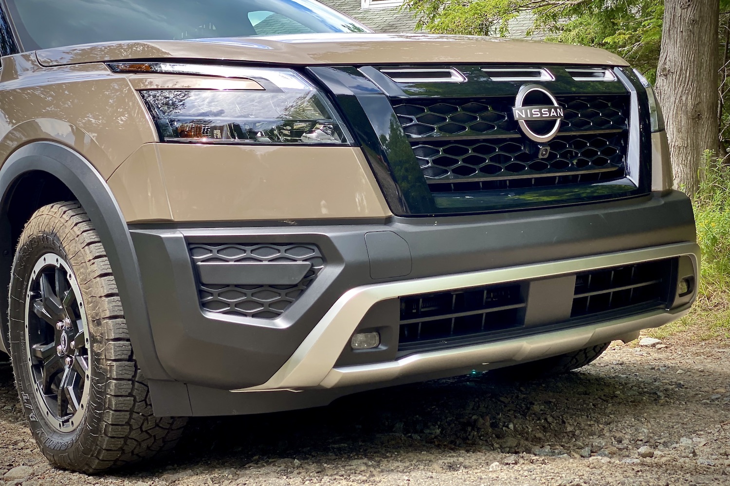Front end of 2023 Nissan Pathfinder Rock Creek close up on grille and headlights on a dirt path.