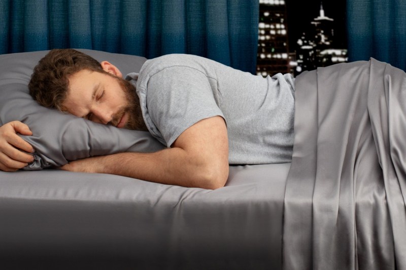 A man sleeps on a set of My Sheets Rock regulator bed sheets.