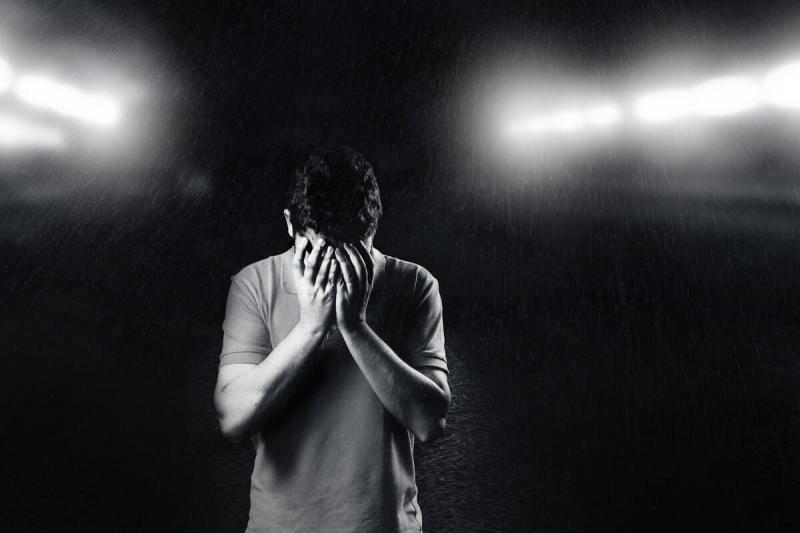 Sad man with face in hands.