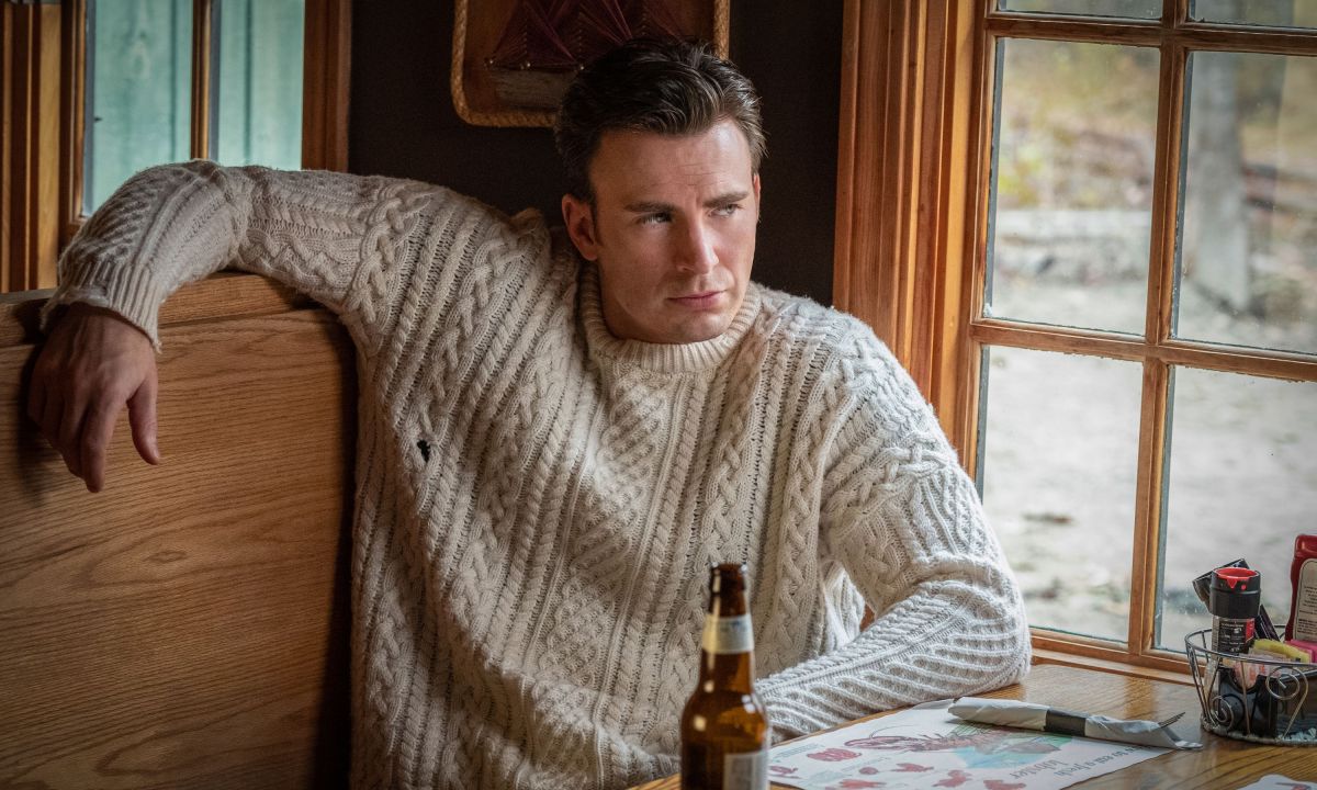 Chris Evans in Knives Out, sitting at a table in a chunky knit sweater