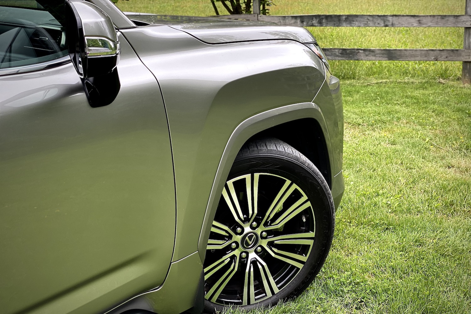 Close up of 2022 Lexus LX 600 front right wheel arch, fender, and wheel on a grassy field.